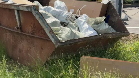 An old rusty container stands motionless in a field overgrown with tall grass Stock Footage 316387899