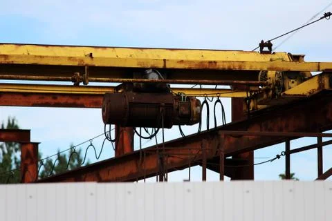Old rusty crane beam in the warehouse under the open sky near the building su Free Stock Photos