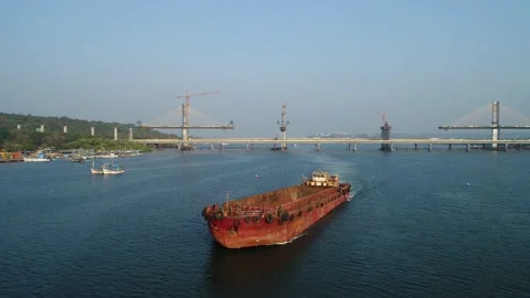 Old rusty dry cargo ship floats on the river near a big bridge. Aerial view. Vidéo 85521447