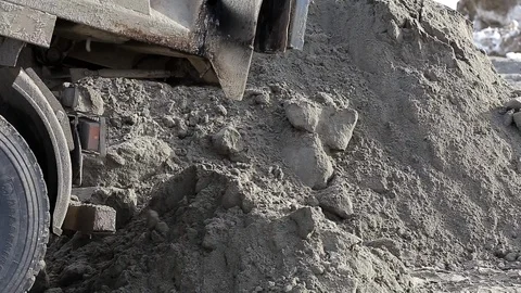 Old rusty dump truck brought frozen earth to winter construction site, unloading Stock Footage 115925289