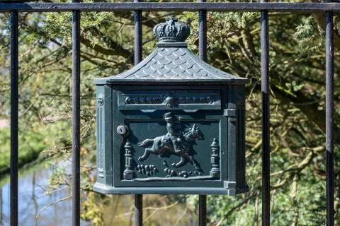 An old, rusty dutch mailbox hangs on a fench Stock Photos