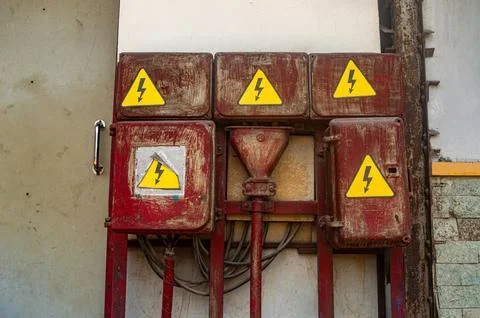 Old, rusty electrical boxes with yellow high voltage warning signs. Industr.. Stock Photos