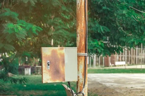 Old rusty electrical power control box on rusted electric pole in the public  Stock Photos