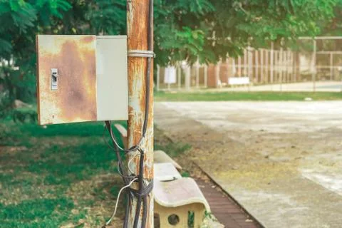 Old rusty electrical power control box on rusted electric pole in the public  Stock Photos