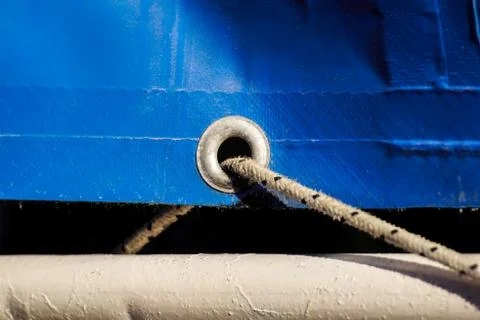 Old rusty eyelets on an aged blue coated plastic canvas Stock Photos