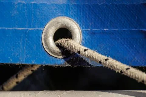 Old rusty eyelets on an aged blue coated plastic canvas Stock Photos