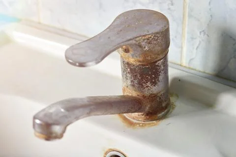 Old, rusty faucet in the kitchen, limestone, scum, need a replacement. Stock Photos