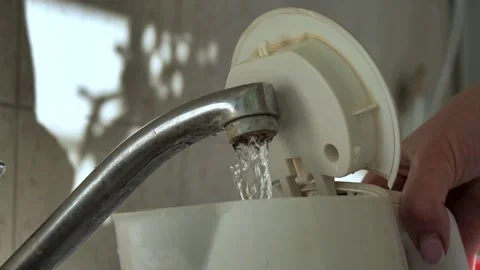 Old rusty faucet from which draws water into white electric kettle Video stock 270519282