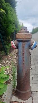 Old rusty fire hydrant with weathered paint beside a sidewalk. Stock Photos