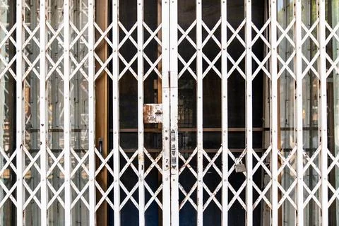 Old rusty folding metal security gate with locked entrance and geometric la.. Stock Photos