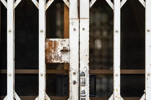 Old rusty folding metal security gate with locked entrance and geometric la.. Stock Photos