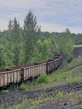 Old rusty freight wagons on a railway track in an industrial landscape. Stock Photos