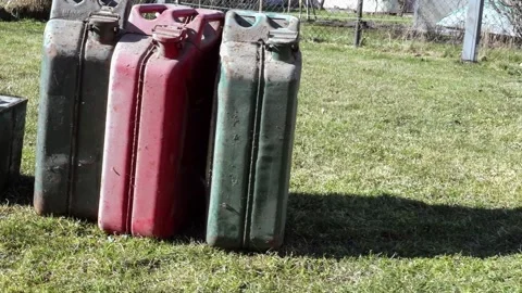 Old Rusty Fuel Cans on Grass Reflecting Global Oil Crisis Impact Stock Footage 333858157