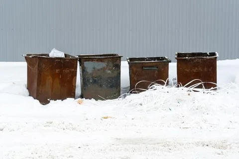 Old rusty garbage containers on the snow. Stock Photos