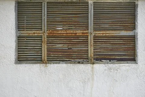 Old rusty gray grille ventilation holes lattice, wall covered with stone chips Stock Photos