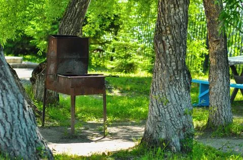 Old rusty grill on the grass between the trees. Stock Photos