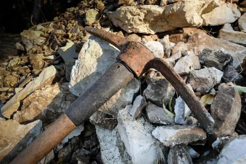 Old rusty hack axe on the heap of rocks in the garden 库存照片