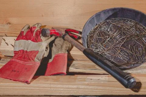 Old rusty hammer and construction gloves laid on wooden board Stock Photos