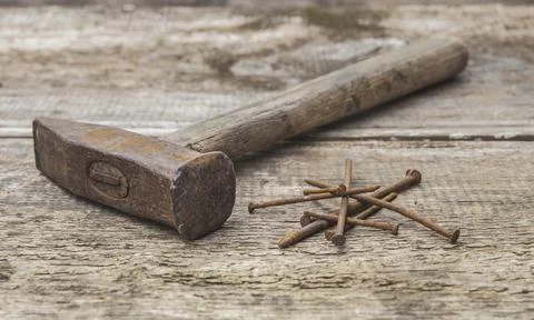 Old rusty hammer and nails on an unpainted wooden table Stock Photos