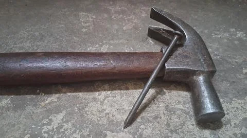 Old rusty hammer resting on concrete surface. Vintage hand tool for Stock Photos