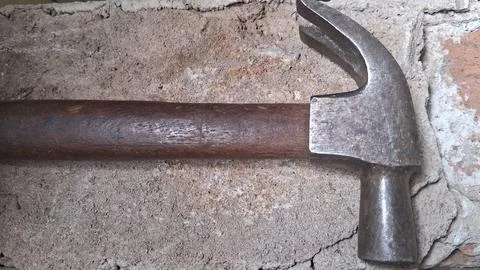 Old rusty hammer resting on stone wall. Vintage hand tool for construction and Stock Photos