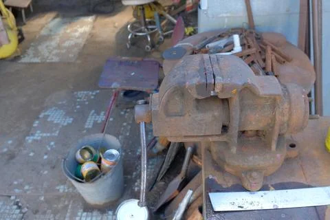 Old rusty hand tools and vintage bench vise in a workshop. Stock Photos