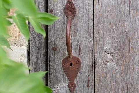 Old rusty handle on the door.Metal handle on wooden door in village. The co.. Stock Photos
