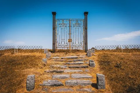 Old rusty iron gate in the middle of a field leading to nowhere. Concept of Stock Photos