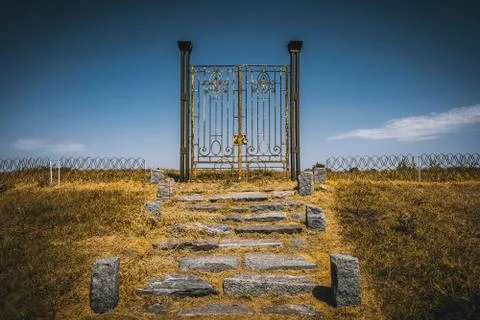 Old rusty iron gate in the middle of a field leading to nowhere. Concept of Stock Photos