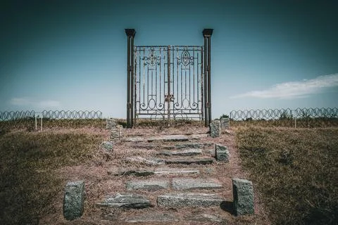 Old rusty iron gate in the middle of a field leading to nowhere. Concept of Stock Photos