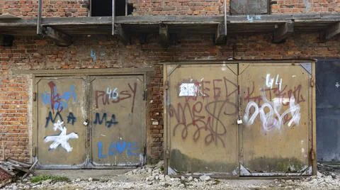 Old rusty iron gate with red brick wall loft warehouse. Slum concept. Backgro Stock Photos