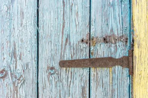 Old rusty iron hinge with nails on wooden door with cracked peeling blue and  Stock Photos