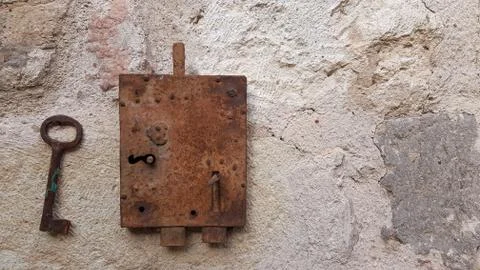 Old rusty key hanging on rough stone background with copy space Stock Photos