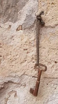 Old rusty key hanging on rough stone background with copy space Stock Photos
