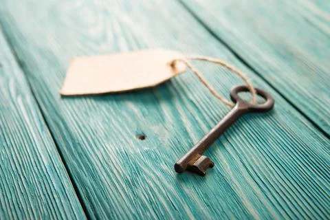 Old rusty key with a paper label on the wooden board Stock Photos