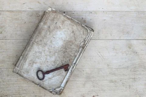Old rusty key on torn book Stock Photos