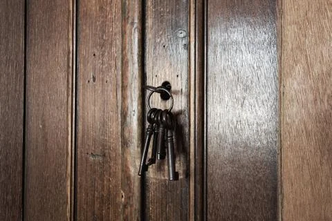 Old rusty keys inside a keyhole of an old antique closet. vintage design Stock Photos