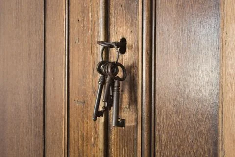 Old rusty keys inside a keyhole of an old antique closet. vintage design 库存照片