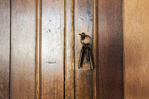 Old rusty keys inside a keyhole of an old antique closet. vintage design Stock Photos