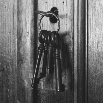 Old rusty keys inside a keyhole of an old antique closet. vintage design black Stock Photos