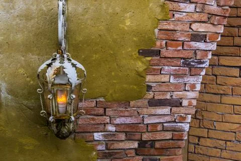 Old rusty lighted lantern on a stone wall, classic architecture and decoratio Foto stock