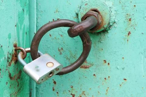 An old, rusty lock attached to a vibrant turquoise door, a fascinating sight to Stock Photos