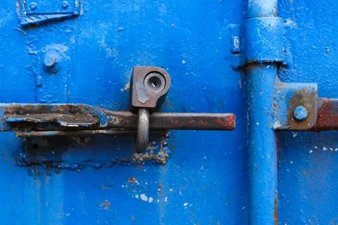 Old rusty lock on the bright blue door of a metal sea container, close-up Photos