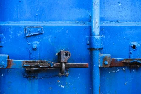 Old rusty lock on the bright blue door of a metal sea container, close-up Photos
