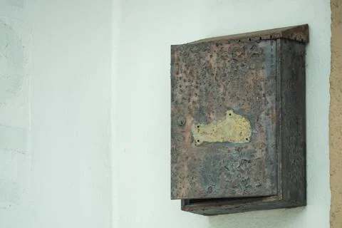 An old, rusty mailbox hangs open on the wall Stock Photos