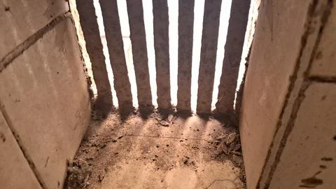Old rusty metal bars blocking bright light in dark room Stock Photos