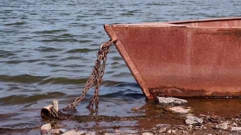 Old rusty metal boat chained on a river bank on a sunny day Stock Footage 128287660
