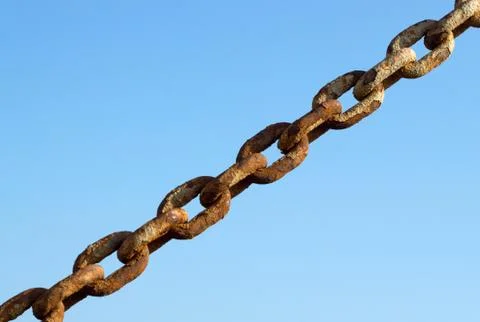 Old rusty metal chain links and a blue sky. Stock Photos