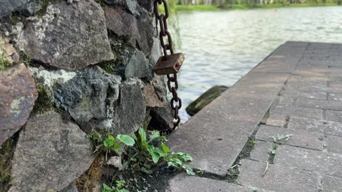 Old Rusty Metal Chain Padlock Hanging On Stone Wall Near Lake Pier Stock Footage 344703342