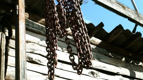 Old rusty metal chains sway in wind in ruined abandoned workshop. Stock Footage 129272156